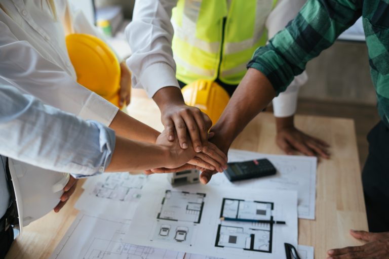 Construction workers, architects and engineers shake hands after completing an agreement in an